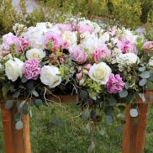 Large pink and white floral arrangement on a wooden stand