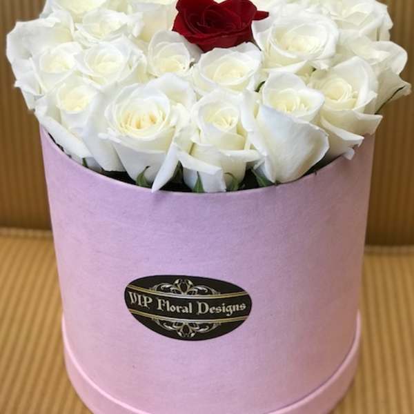 White roses with one red rose in a pink hatbox