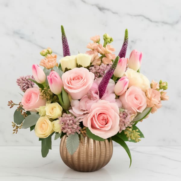 Pink and cream floral arrangement in a ribbed gold vase