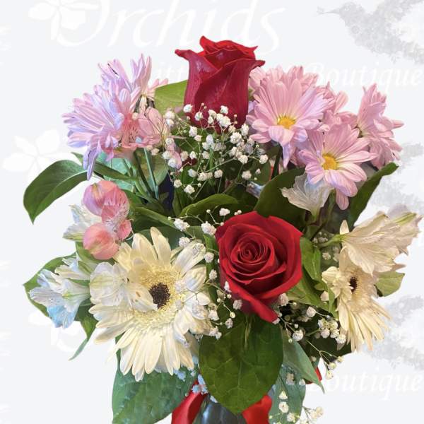 Bouquet of red roses, pink daisies, and white gerbera daisies in a vase