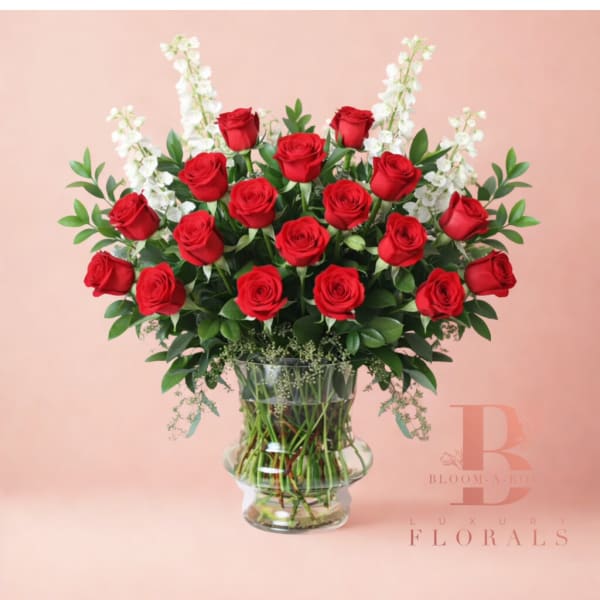 Red roses arranged in a clear glass vase with white accent flowers