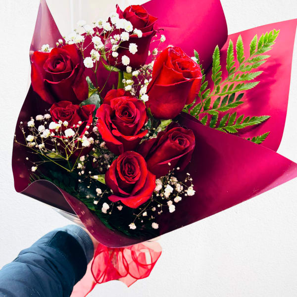 Bouquet of red roses with white baby's breath in burgundy wrap