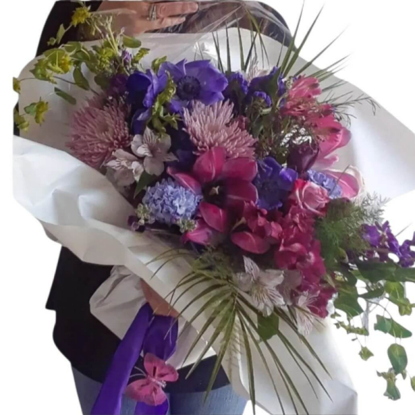 Bouquet of purple, pink, and blue flowers wrapped in white paper