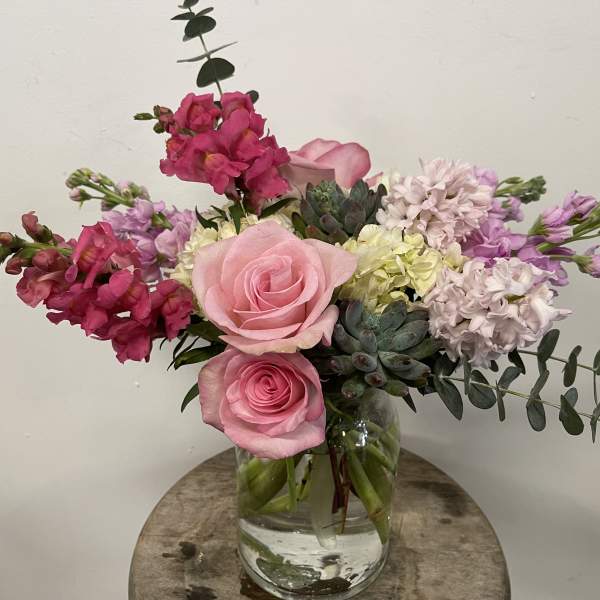 Pink roses and mixed blooms arranged in a clear glass vase