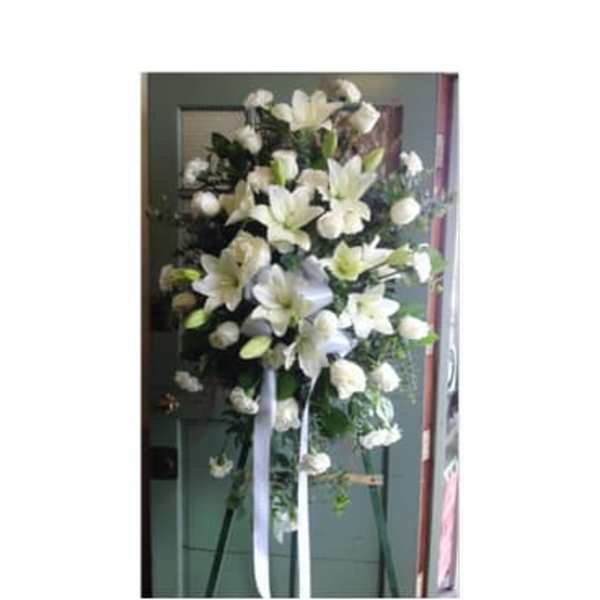 Tall white lily standing spray on an easel with ribbon streamers