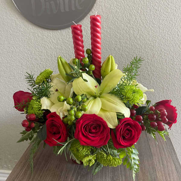 Red roses and pale lilies arranged with candles in a low centerpiece