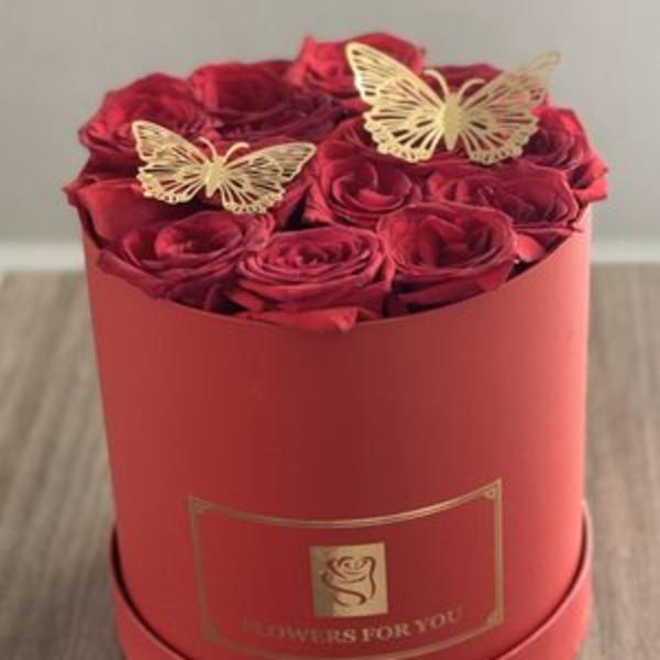 Red roses arranged in a round red box with butterfly toppers