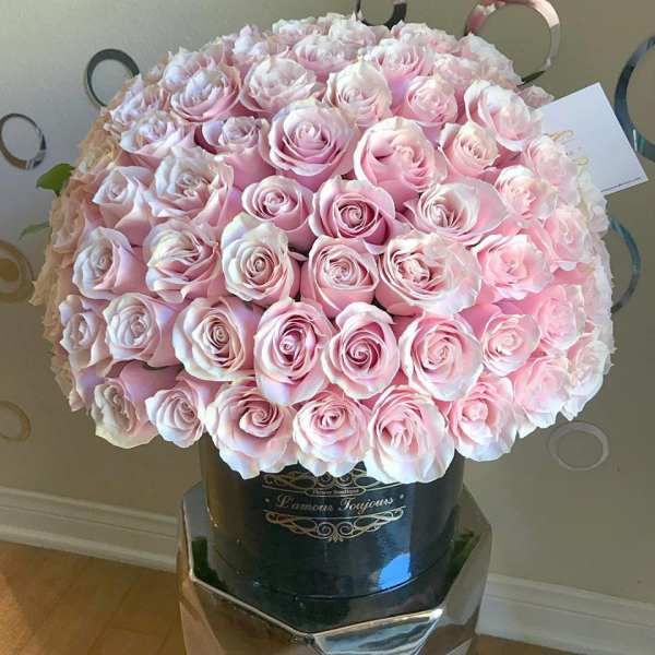Large hatbox arrangement of tightly clustered pale pink roses in a black cylinder box.