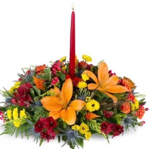 Floral centerpiece with a tall red candle and orange lilies