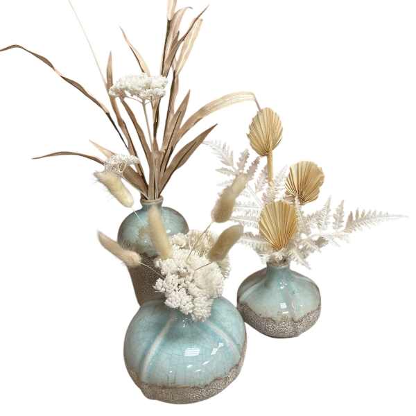 Three dried floral arrangements in blue ceramic vases