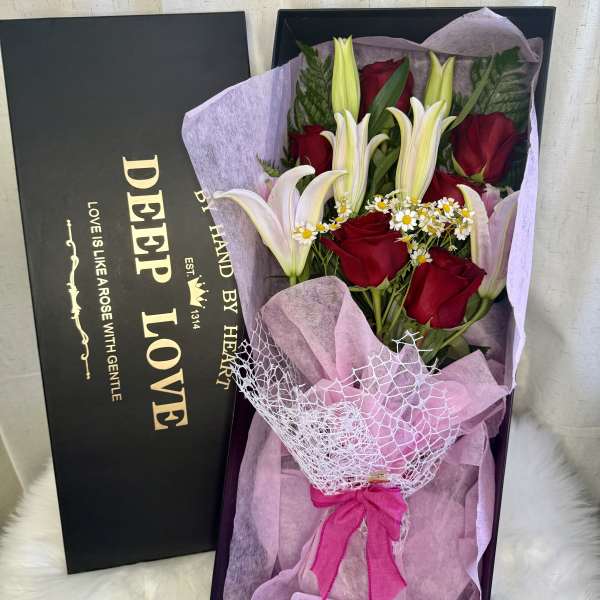 Red roses and white lilies in a gift box with pink wrapping
