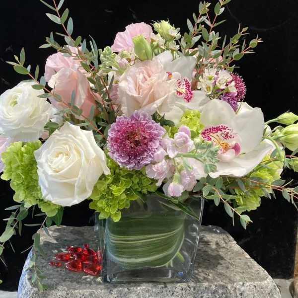 Mixed bouquet of white, pink, and green flowers in a clear glass vase