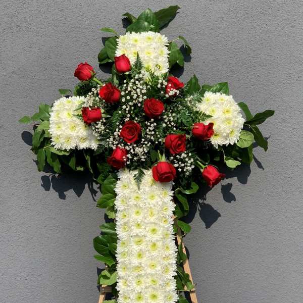 Cross-shaped floral tribute with white chrysanthemums and red roses on an easel