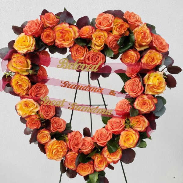 Heart-shaped rose wreath on a stand with pink ribbons