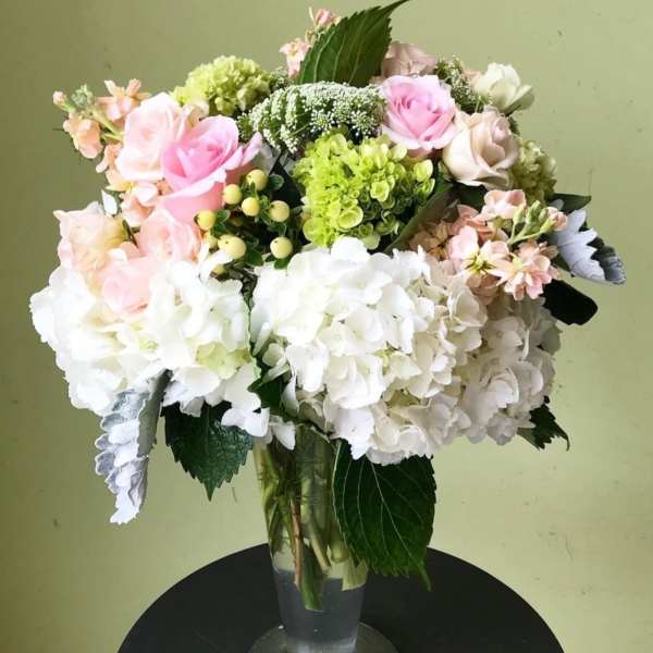 Bouquet of pink and white roses with hydrangeas in a clear glass vase