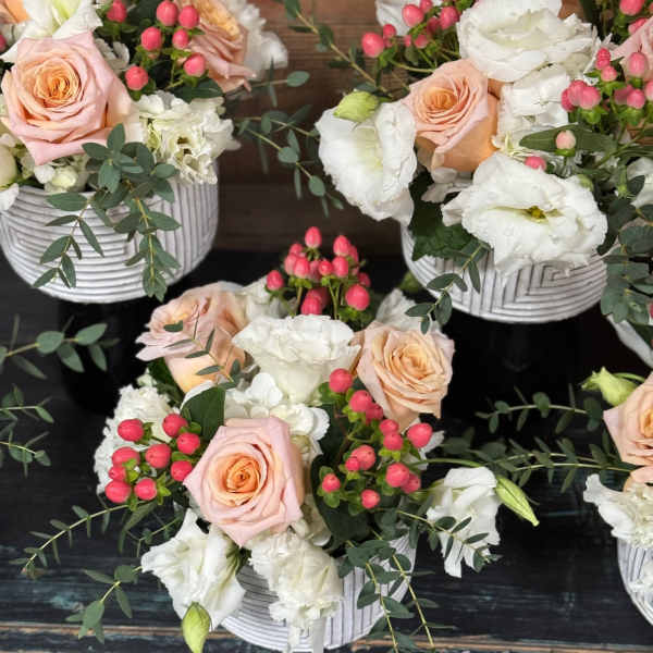 Pink roses and white blooms arranged in white ribbed containers