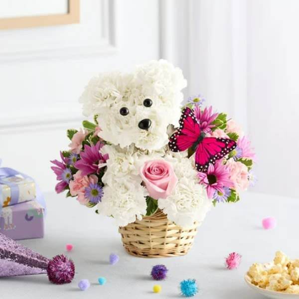 White teddy bear made of flowers in a wicker basket with pink and purple blooms