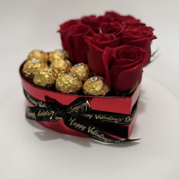 Red roses and gold-wrapped chocolates in a heart-shaped box
