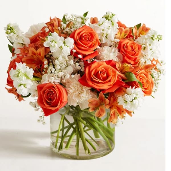 Bouquet of orange roses and white flowers in a clear glass vase
