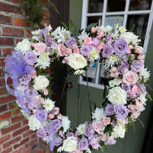 Heart-shaped floral wreath with lavender, pink, and white flowers on an easel
