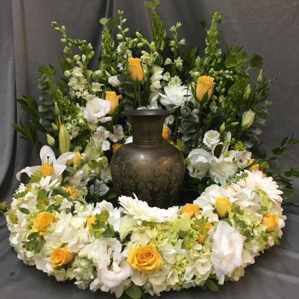 White and yellow floral wreath around a dark urn