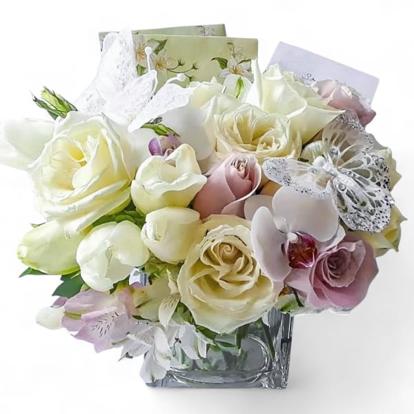 Bouquet of white and blush roses with orchids in a clear square vase