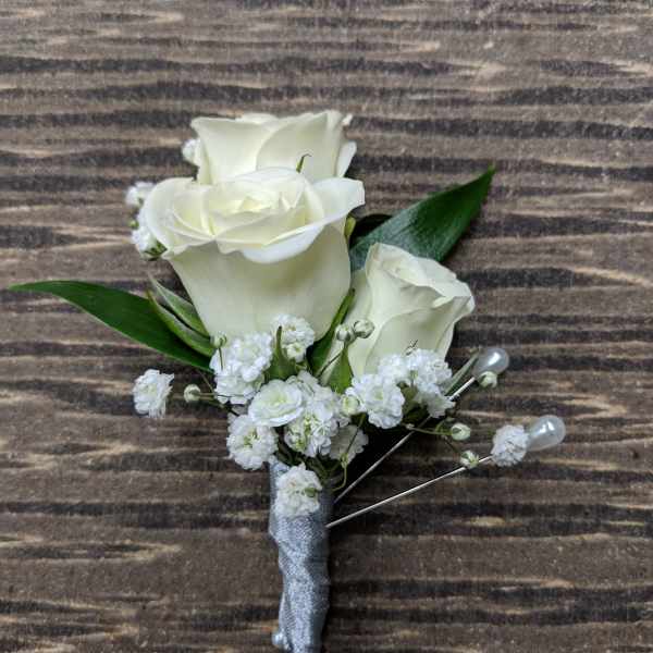 White rose boutonniere with small white filler flowers and silver wrap