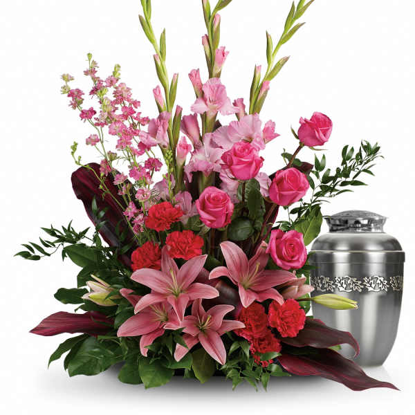 Pink lilies and roses arranged beside a silver urn