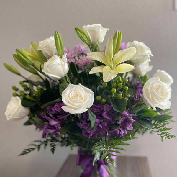 White roses and lilies with purple flowers in a glass vase