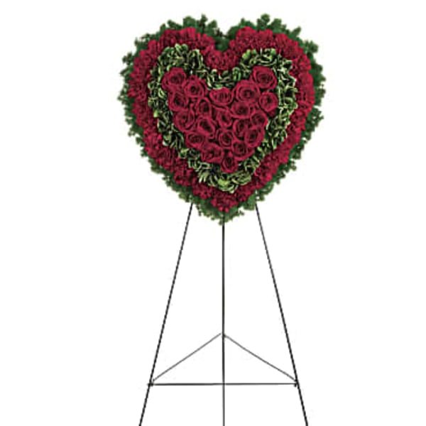Heart-shaped standing floral spray with red roses and greenery on an easel