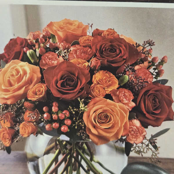 Bouquet of orange and red roses in a glass vase