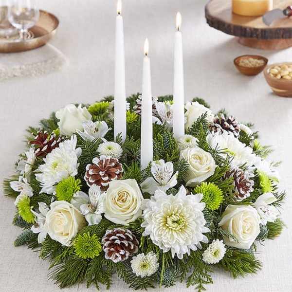 White floral candle centerpiece with pinecones and three taper candles