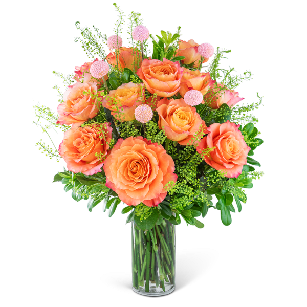 Orange roses in a clear glass vase with pink accent flowers