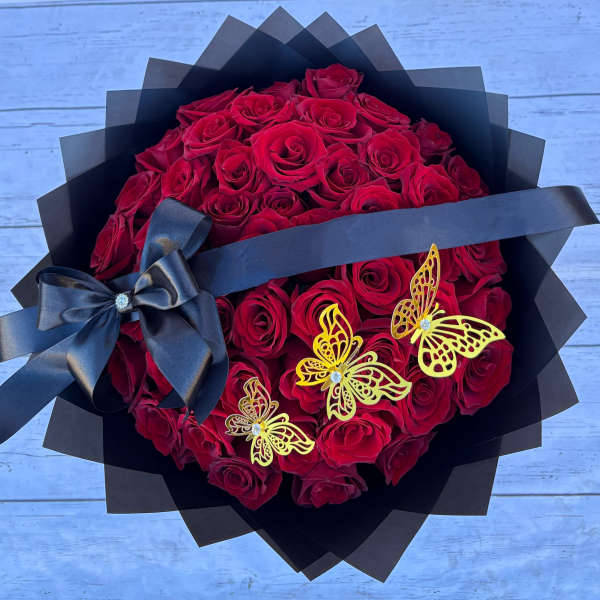 Bouquet of red roses wrapped in black paper with a black ribbon and butterfly accents