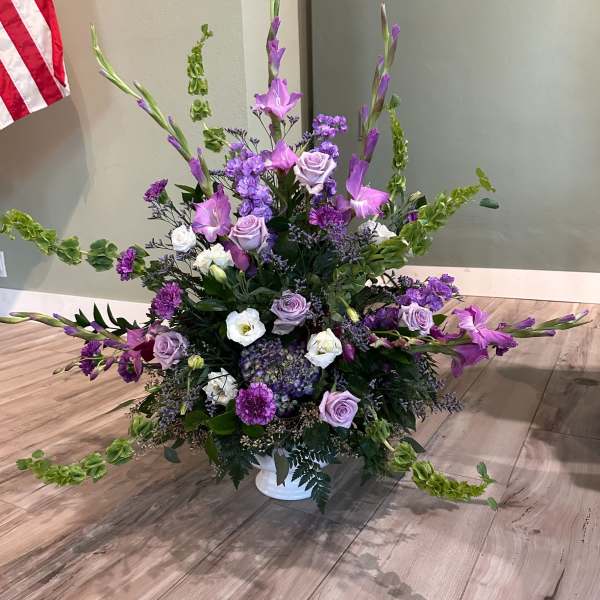 Large purple and white floral arrangement in a white vase