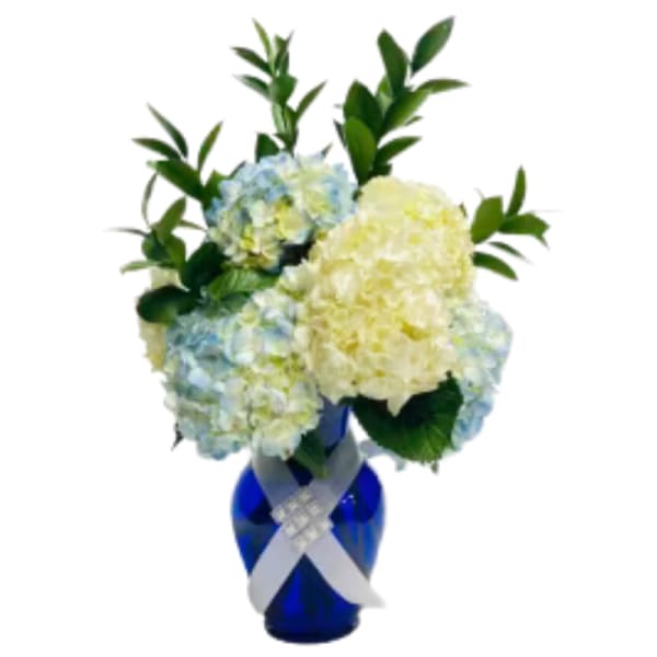 Blue and white hydrangea arrangement in a cobalt vase with a ribbon