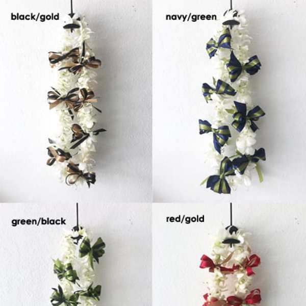Four white floral leis with ribbon bows in different color combinations