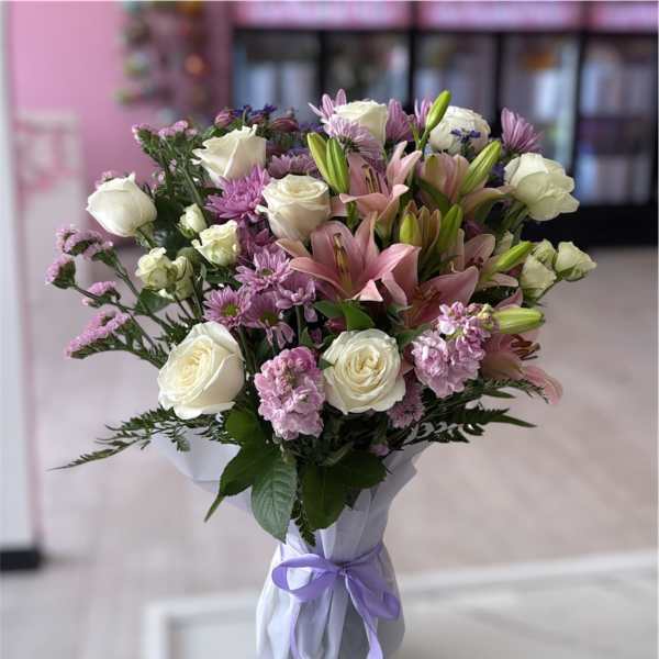 Bouquet of white roses, pink lilies, and purple flowers in wrapped paper