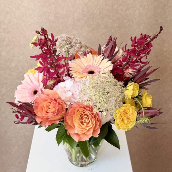 Mixed bouquet of roses and gerbera daisies in a clear glass vase