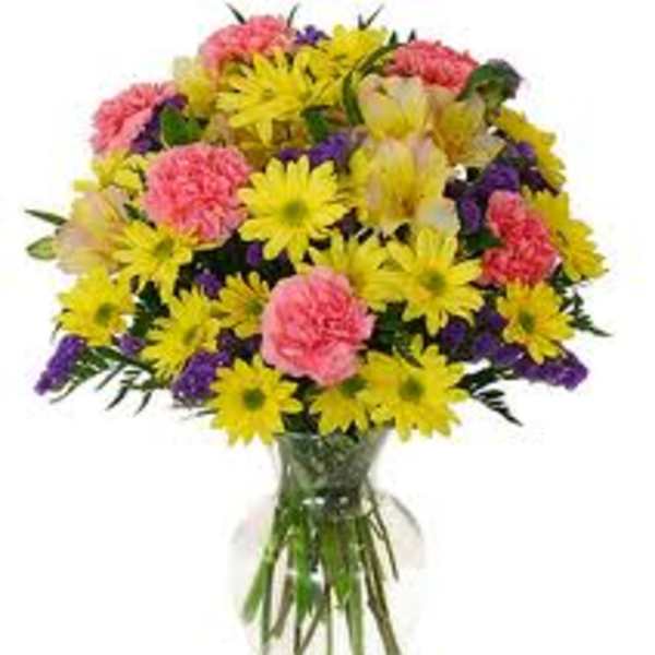 Bouquet of yellow daisies and pink carnations in a clear glass vase