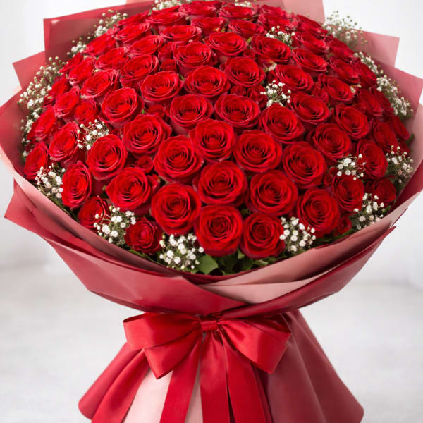 Large bouquet of red roses wrapped in pink paper with a red ribbon