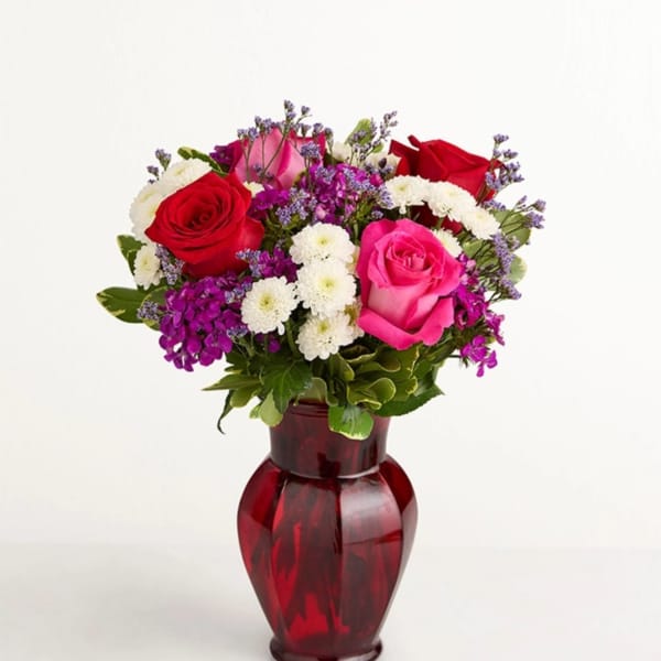 Bouquet of red and pink roses in a red glass vase