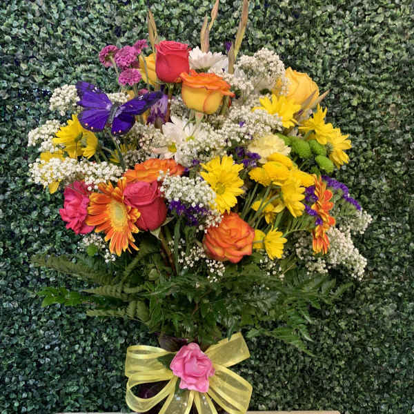 Mixed bouquet in a dark vase with a yellow ribbon
