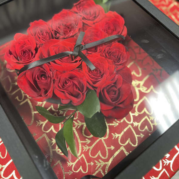 Red roses arranged in a black framed box with a ribbon