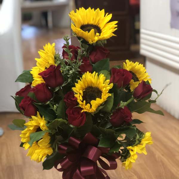 Bouquet of red roses and yellow sunflowers in a glass vase
