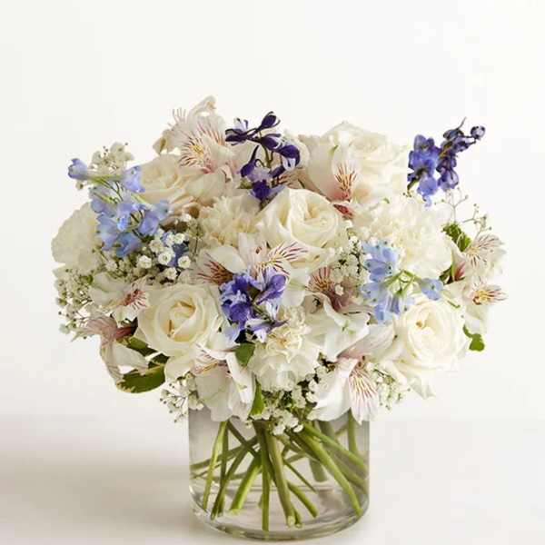 White and blue mixed bouquet in a clear glass vase