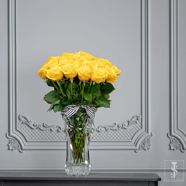Bouquet of yellow roses in a clear glass vase with a striped ribbon