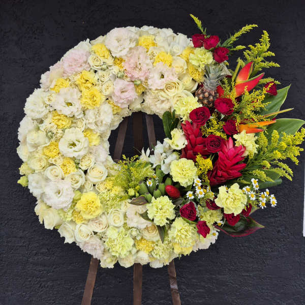 Large floral wreath with cream, yellow, pink, and red flowers on an easel