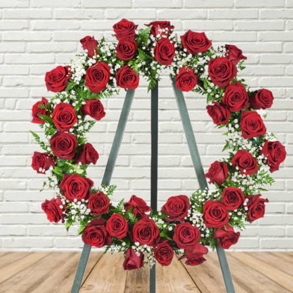 Heart-shaped wreath of red roses on a metal stand