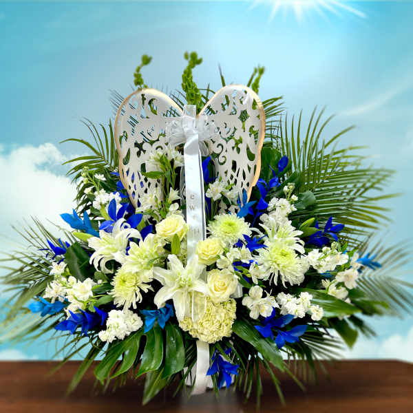 White and blue floral arrangement with a decorative angel wing topper